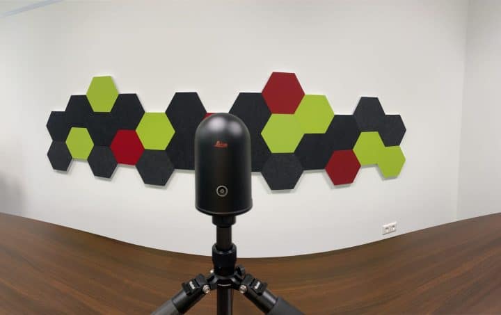 Leica 3D-Scanner auf Stativ vor bunten Hexagon-Akustikpaneelen